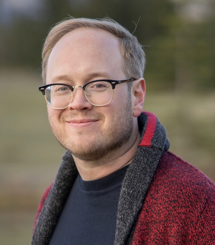 a man wearing glasses and smiling at the camera