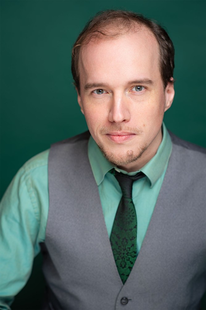 Andrew Wade wearing a suit and tie smiling and looking at the camera