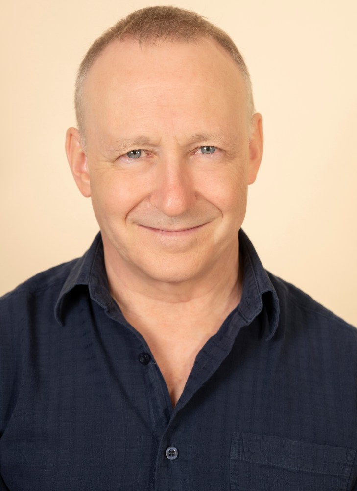 a man wearing glasses and smiling at the camera