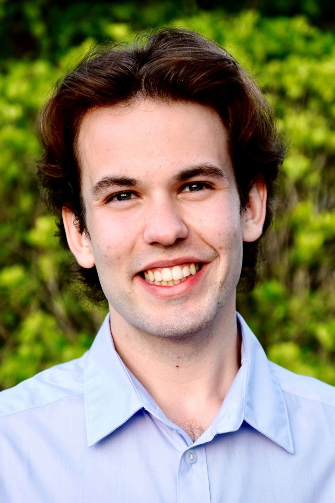 a man wearing a blue shirt and smiling at the camera
