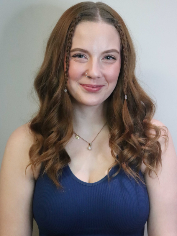 Smiling woman with wavy hair and braids, wearing a blue top.